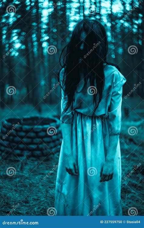 Girl In Image Of Scary Zombie Stands In Dark Forest Near Stone Well