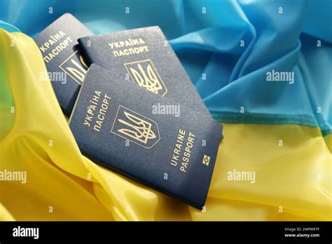 Three Ukrainian Biometrical Passports On Folded Waving Flag Of Ukraine