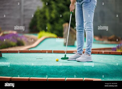 Woman Playing Mini Golf And Trying Putting Ball Into Hole Summer