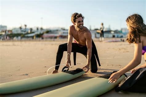 Premium Photo Couple Is Kneeling Next To Surfboards On A Beach And