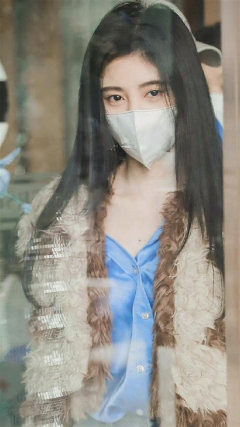 A Woman Wearing A Face Mask Looking Through A Window