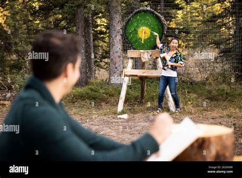 Couple having axe throwing competition Stock Photo - Alamy