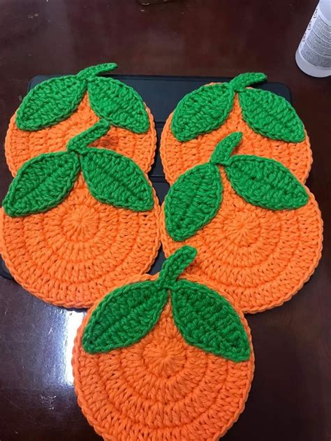 Three Crocheted Coasters With Green Leaves On Them Sitting On Top Of A