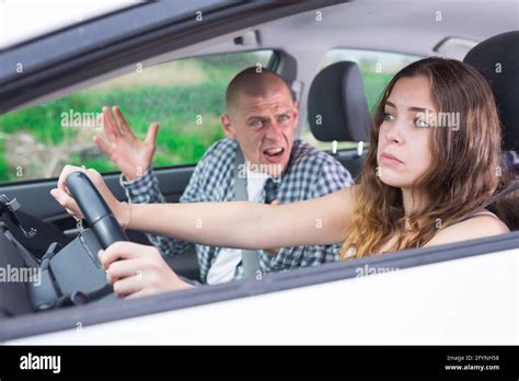 Confused Young Woman Driving Car Against Background Of Angry Screaming