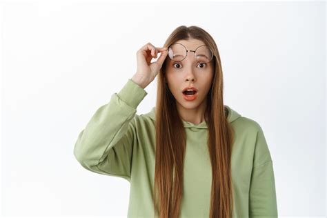 Une fille caucasienne surprise enlève des lunettes et regarde avec