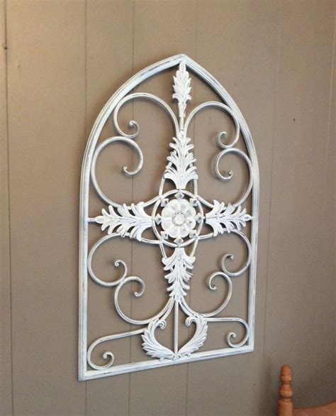 A White Metal Wall Hanging With An Ornate Design On It S Side And A