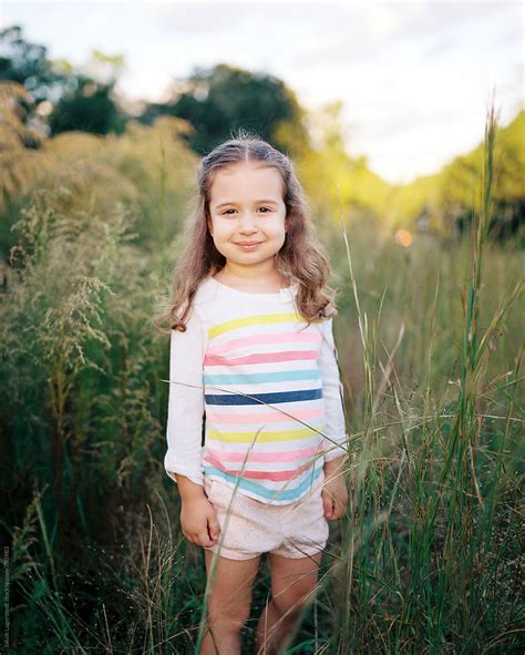 Portrait Of A Beautiful Young Girl Playing In A Field Of Tall Grass