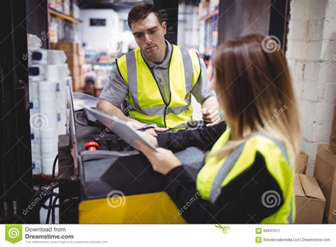 Trabajador De Warehouse Que Habla Con El Conductor De La Carretilla