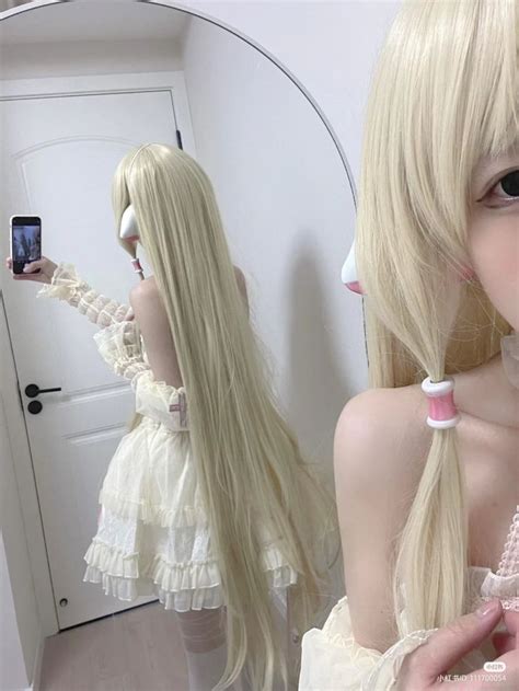 A Woman With Long Blonde Hair Is Taking A Selfie In Front Of A Mirror