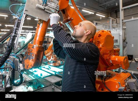 Engineer Doing Maintenance On A Automatic Robot Arms In Automotive