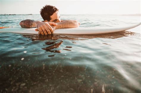 Jeune Mec Allongé Sur Une Planche De Surf Dans L eau Photo Gratuite