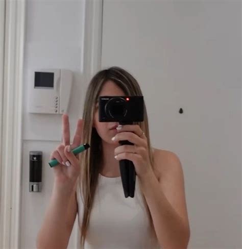 A Woman Taking A Selfie In Front Of A Mirror With A Camera And Pen