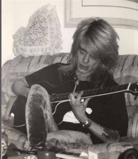 A Man Sitting On Top Of A Couch Holding A Guitar