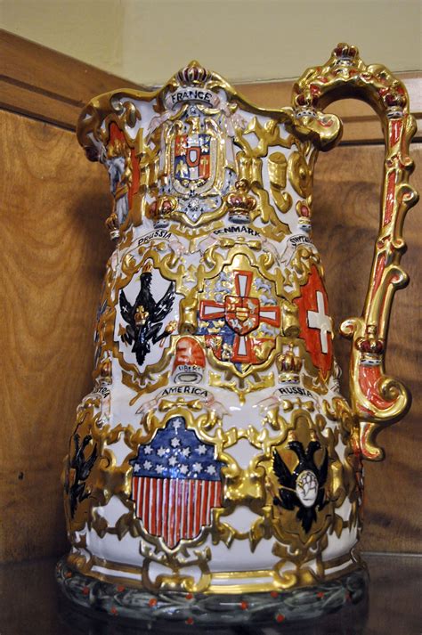 An Ornate Gold And White Vase With American Flags On The Front Is