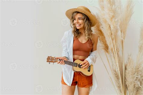 Smiling Graceful Woman In Summer Outfit With Straw Hat Playing Ukulele