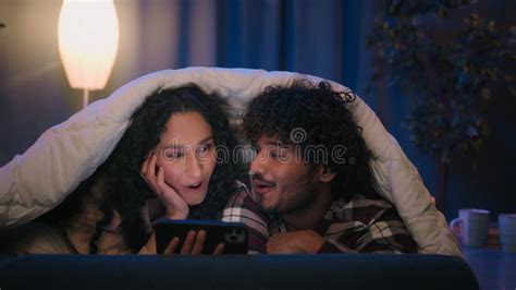 Multiracial Couple Man And Woman At Night Home Using Mobile Phone