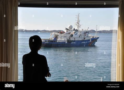 A Woman Looking Out The Window Of Her House At The Greenpeace Ship In