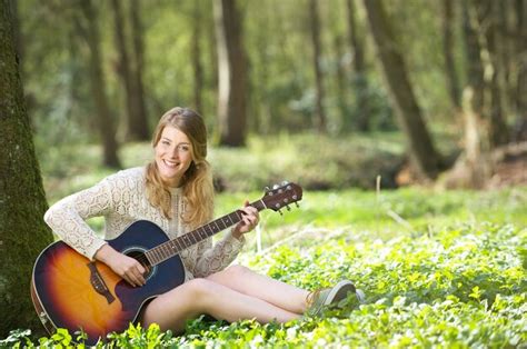 Retrato De Una Mujer Joven Feliz Tocando La Guitarra Al Aire Libre