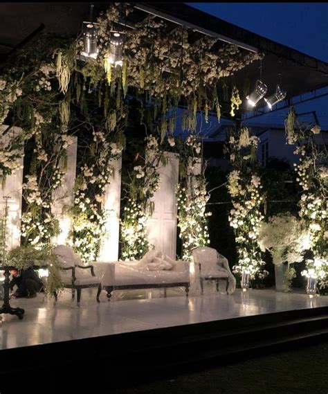 An Outdoor Stage Decorated With White Flowers And Greenery