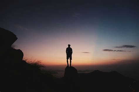 Silhouette Of A Man On Top Of A Mountain At Sunset