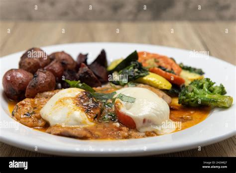 Veal Escalope Drenched In Tomato Sauce Served With Roasted Vegetables And Seasoned Potatoes For