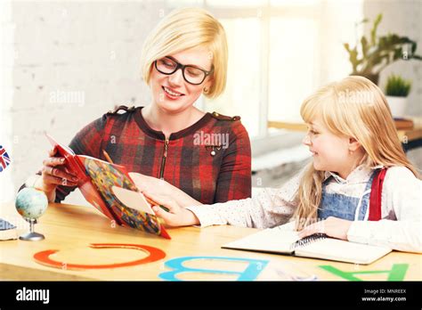 Kid girl réussie qui étudient le français langue avec elegant blonde enseignante une table avec