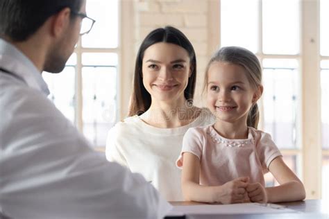 Smiling Mom And Small Daughter Have Consultation With Doctor Stock