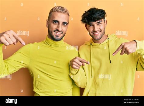 Homosexual Gay Couple Standing Together Wearing Yellow Clothes Looking Confident With Smile On