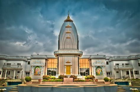 a large building with a fountain in front of it and cloudy skies above ...