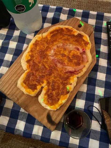 A Pizza Sitting On Top Of A Wooden Cutting Board Next To A Bottle Of Soda