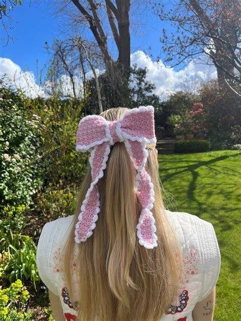 The Back Of A Woman S Head Wearing A Pink And White Crocheted Bow