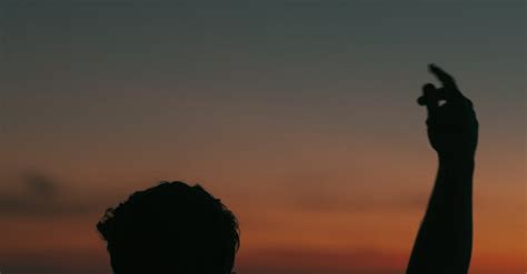 Silhouette Of A Man Rising A Hand Against The Sky At Dusk · Free Stock