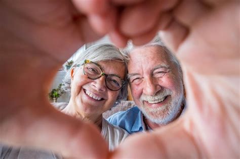 Casal de dois idosos velhos e felizes se divertindo em casa no sofá