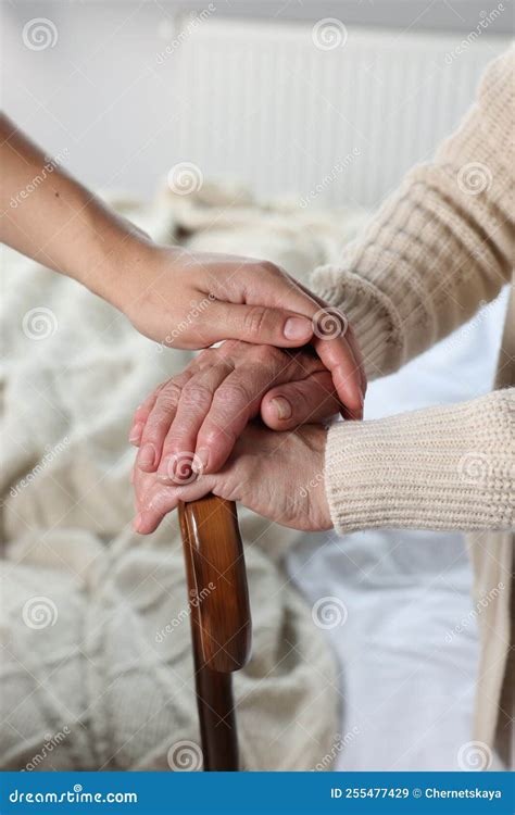 Caregiver And Elderly Woman With Walking Cane At Home Closeup Stock