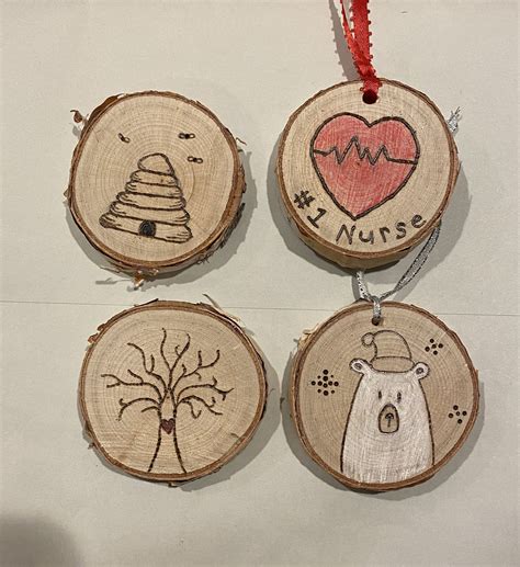 Four Wood Slices With Designs On Them Hanging From A Red Ribbon And