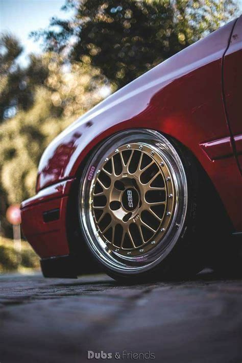 A Red Car With Gold Rims Parked On The Side Of The Road In Front Of