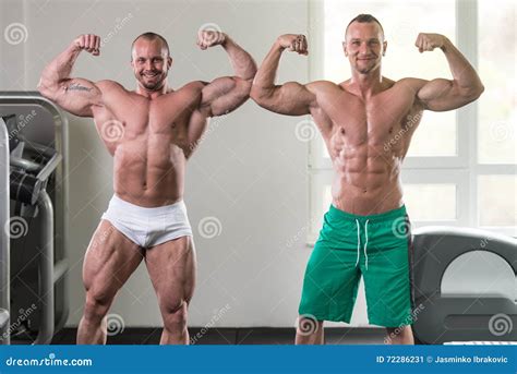 Dois Homens Musculares Que Dobram Os M Sculos No Gym Imagem De Stock