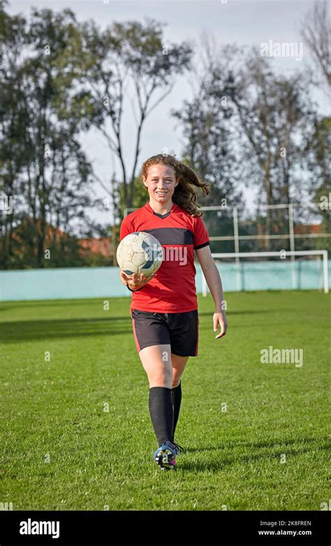 Happy girl walking with soccer ball on field Stock Photo - Alamy