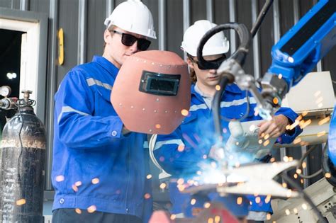 Premium Photo Industrial Workers Working With Robotic Arm Welding