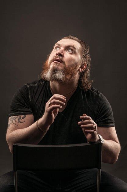 Premium Photo Bearded Man Sitting On Chair Against Black Background