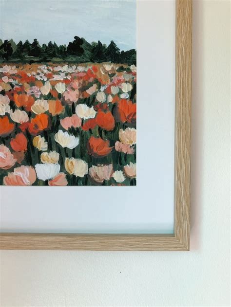 an oil painting of tulips in a field is hanging on the wall next to a ...