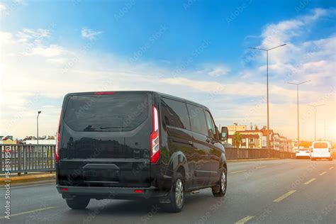 Black modern passenger charter van with a small delivery moves fast on ...