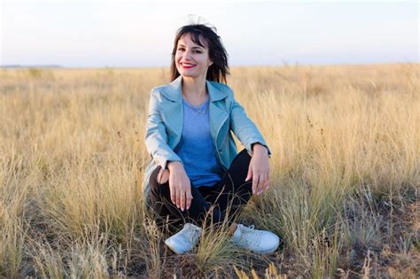 Premium Photo Portrait Of Woman Sitting On Grass Against Sky