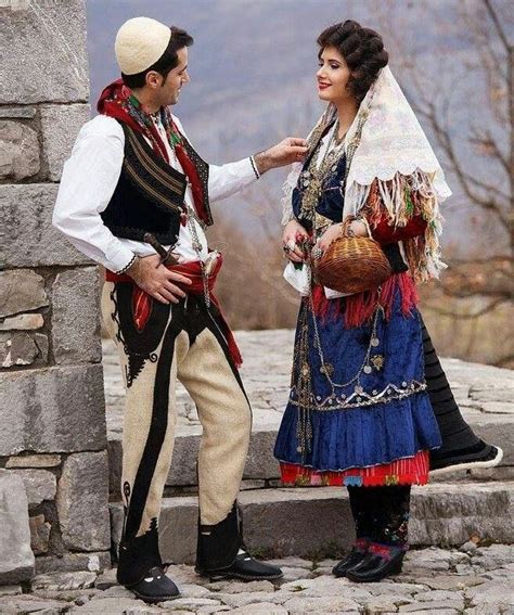 A Man And Woman Dressed In Costume Standing Next To Each Other On Stone