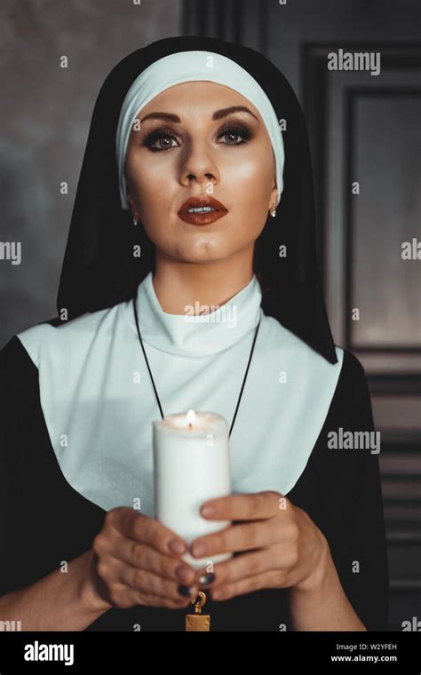 Young Catholic Nun Is Holding Candle In Her Hands Photo On Black