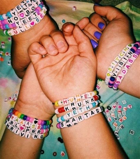 Two Hands Holding Each Other While Wearing Bracelets That Spell Out