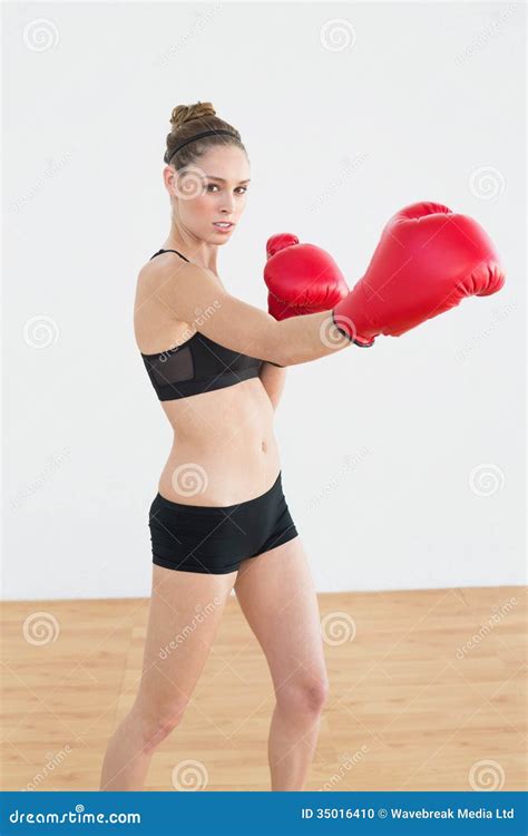 Concentrated Fit Woman Wearing Boxing Gloves While Posing In Sports