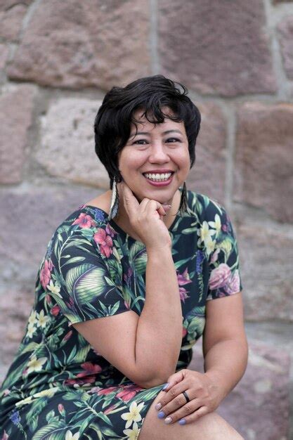 Premium Photo Portrait Of Smiling Woman Sitting Against Stone Wall