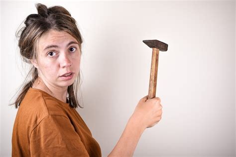 Premium Photo Surprised Woman Holding A Hammer In Her Hands Who Does