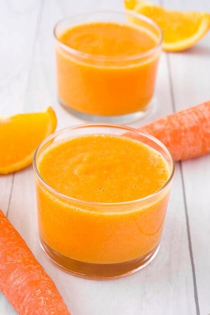 Premium Photo Orange Apple And Carrots Smoothie On White Wooden Table